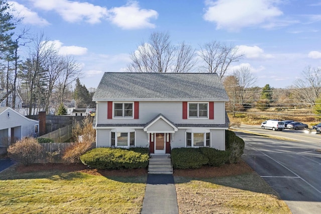 view of front of property with a front yard, roof with shingles, and fence