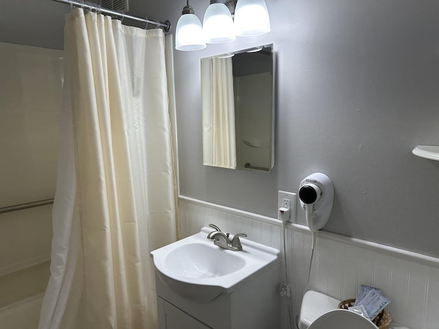 bathroom with toilet, vanity, a shower with shower curtain, and wainscoting