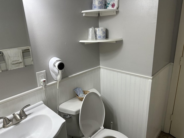 bathroom with a wainscoted wall, a sink, and toilet