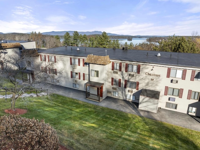 rear view of house with a water and mountain view and a yard