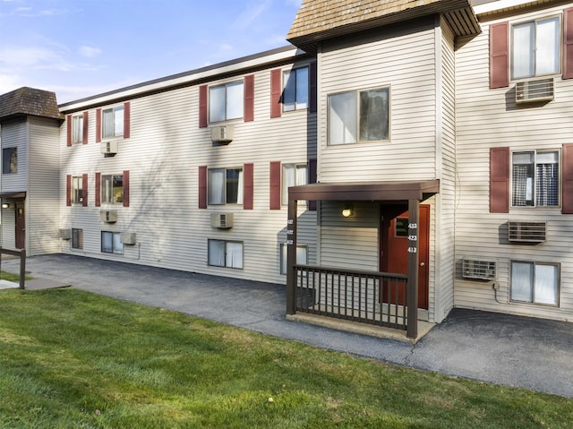 view of property with a front lawn and a wall mounted AC