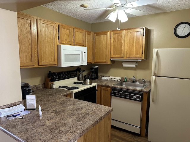 kitchen with dark countertops, white appliances, a sink, and a textured ceiling