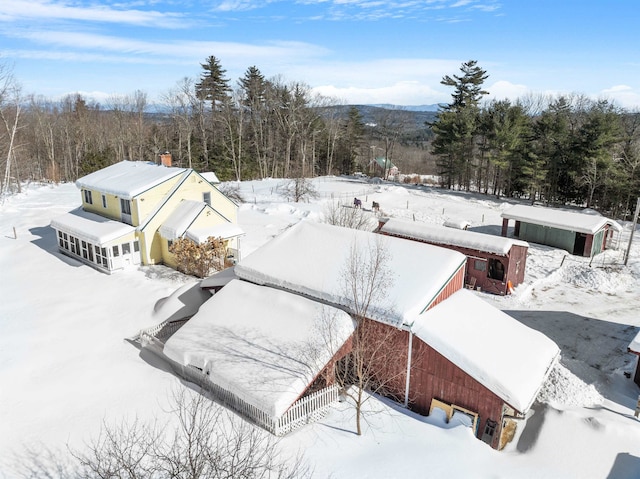 snowy aerial view featuring a wooded view