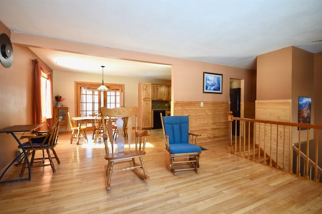 living area with a wainscoted wall, light wood-style flooring, a fireplace, and an upstairs landing