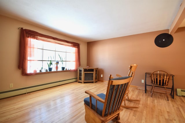 living area with baseboard heating, baseboards, and wood finished floors