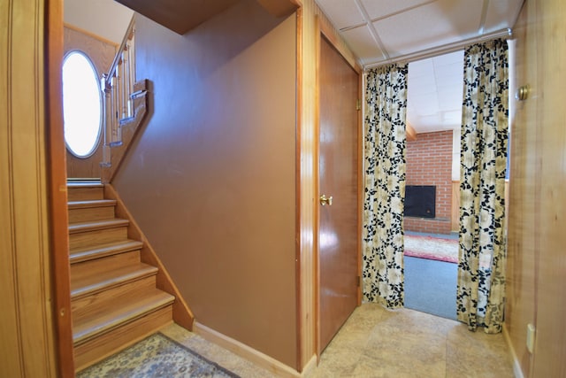 interior space with a paneled ceiling, a fireplace, stairway, and baseboards