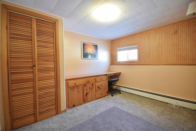 office space featuring a baseboard heating unit, light carpet, and built in study area