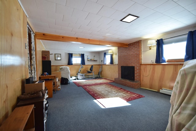 living area with a baseboard heating unit, dark colored carpet, a fireplace, and wood walls