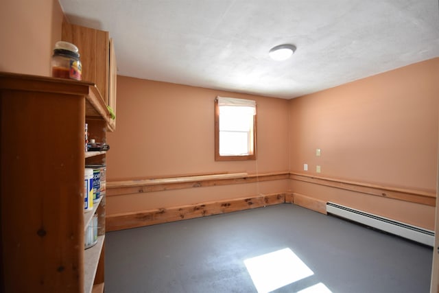 unfurnished room with a baseboard heating unit and concrete flooring