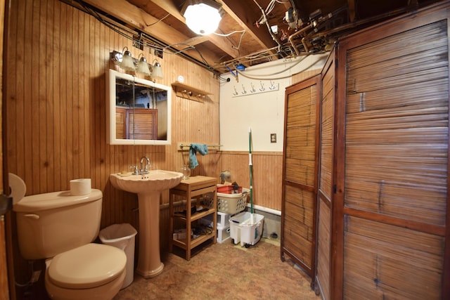 bathroom featuring toilet, wooden walls, and wainscoting