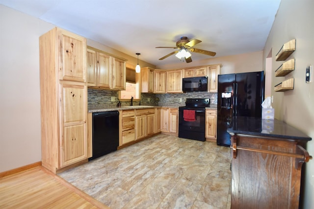 kitchen with pendant lighting, light brown cabinets, a sink, and black appliances