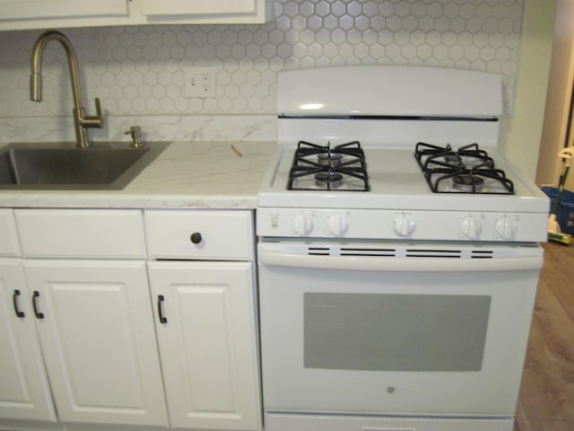 kitchen featuring tasteful backsplash, a sink, white cabinetry, and white range with gas cooktop