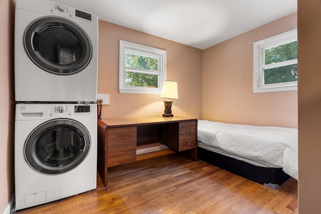 clothes washing area with light wood-type flooring, laundry area, and stacked washer and clothes dryer