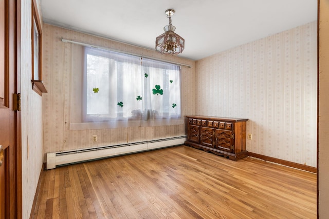 spare room with a baseboard radiator, baseboards, light wood finished floors, and wallpapered walls