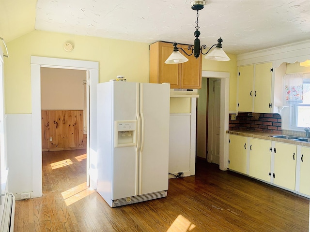 kitchen with white refrigerator with ice dispenser, wood finished floors, hanging light fixtures, a baseboard heating unit, and a sink