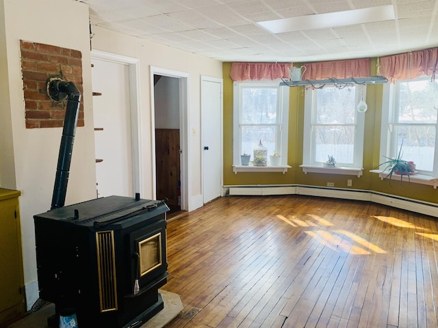 interior space with baseboard heating, wood finished floors, and a wood stove