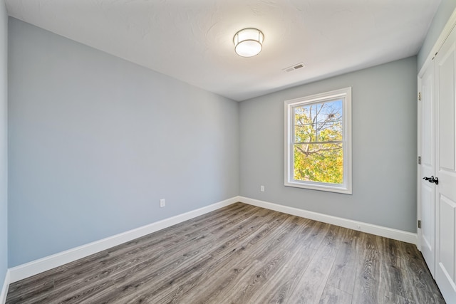 unfurnished bedroom featuring a closet, wood finished floors, visible vents, and baseboards