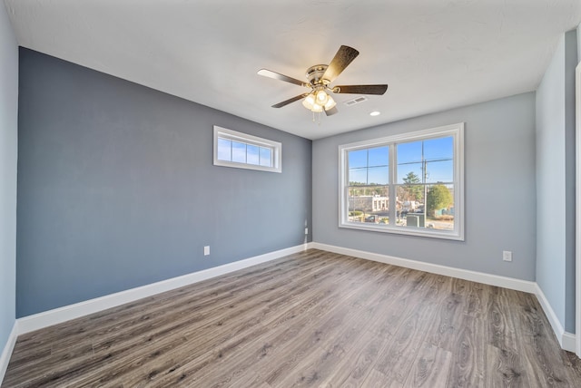 unfurnished room featuring a ceiling fan, visible vents, baseboards, and wood finished floors