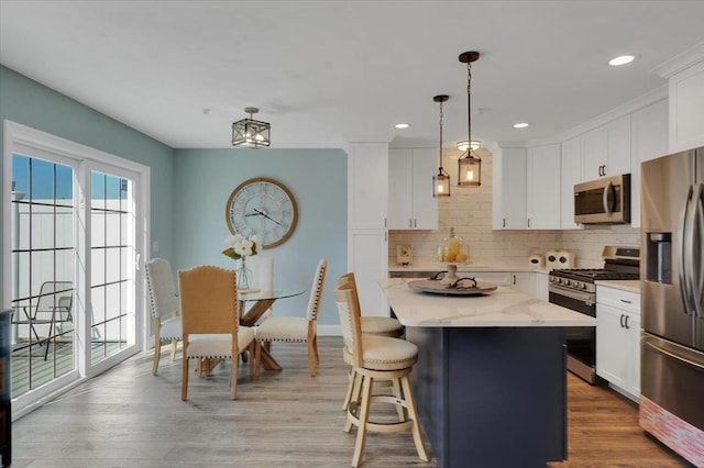 kitchen featuring hanging light fixtures, appliances with stainless steel finishes, white cabinets, and a center island