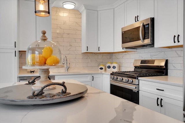 kitchen with appliances with stainless steel finishes, white cabinets, hanging light fixtures, and tasteful backsplash