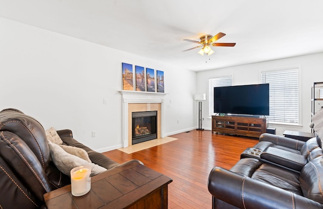 living room with baseboards, a fireplace with flush hearth, a ceiling fan, and wood finished floors