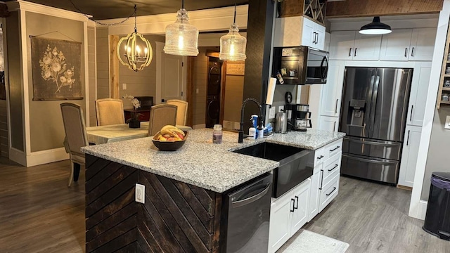 kitchen featuring dishwashing machine, white cabinets, light stone countertops, stainless steel fridge, and decorative light fixtures