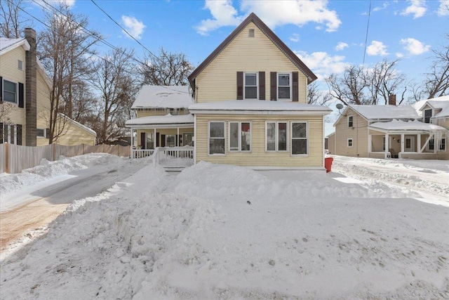 snow covered rear of property with a porch