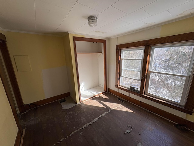 unfurnished bedroom with a closet, crown molding, baseboards, and wood finished floors