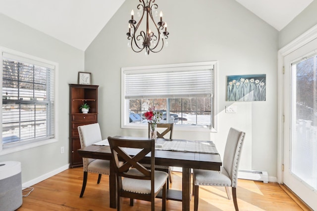 dining space featuring a baseboard heating unit, vaulted ceiling, plenty of natural light, and light wood-style floors