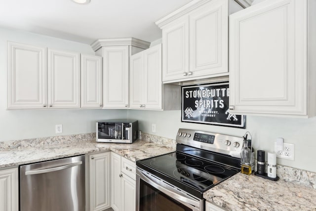 kitchen featuring stainless steel appliances, white cabinets, and light stone counters