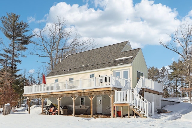 snow covered back of property featuring a shingled roof, stairway, and a wooden deck