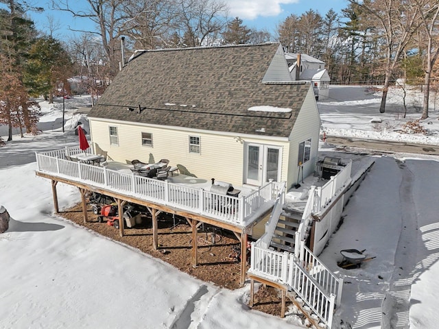 snow covered back of property featuring a shingled roof, stairway, and a wooden deck