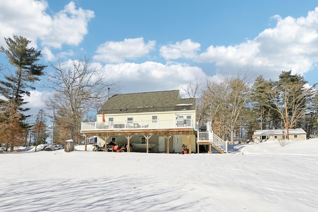 snow covered house with stairs and a wooden deck