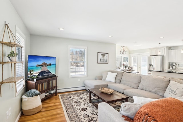 living room featuring plenty of natural light, a baseboard radiator, light wood-style flooring, and recessed lighting