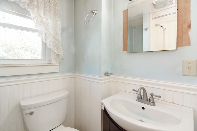 bathroom featuring toilet, vanity, and wainscoting