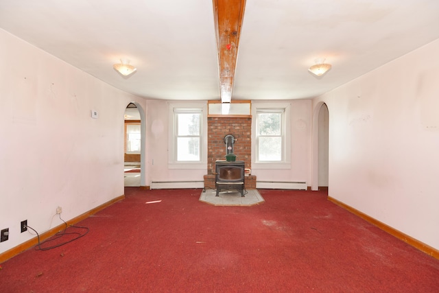 unfurnished living room featuring arched walkways, a wood stove, and carpet flooring