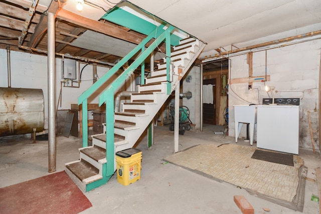 unfinished below grade area featuring washer / clothes dryer, a sink, stairway, and heating fuel