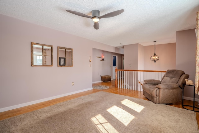 living area featuring light wood-type flooring, a textured ceiling, and baseboards