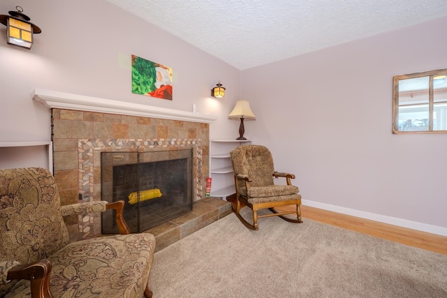 sitting room with a textured ceiling, baseboards, a fireplace, and wood finished floors