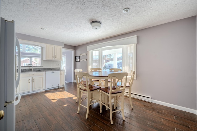 dining space featuring baseboards, a textured ceiling, a baseboard radiator, and wood tiled floor