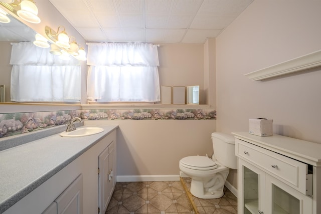 half bath with tile patterned flooring, baseboards, vanity, and toilet