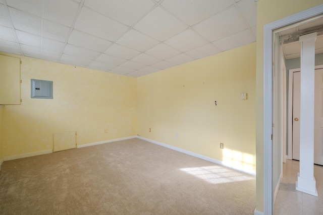 spare room with baseboards, light colored carpet, a paneled ceiling, and electric panel