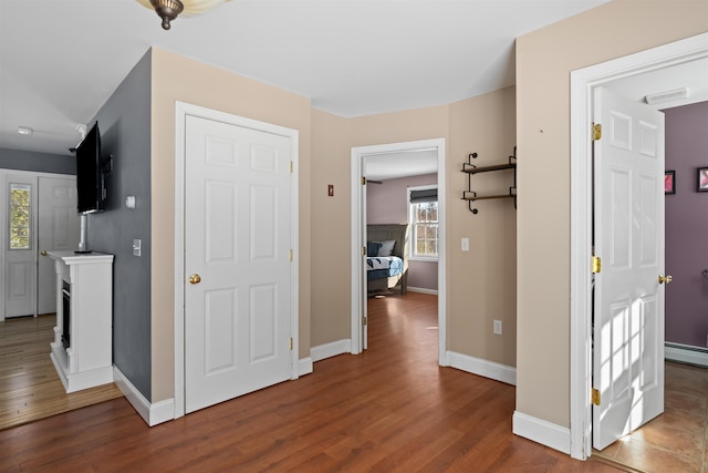 hall with dark wood-style floors, a baseboard radiator, and baseboards