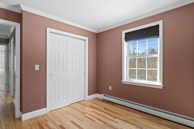 unfurnished bedroom with light wood finished floors, baseboards, a baseboard radiator, crown molding, and a closet