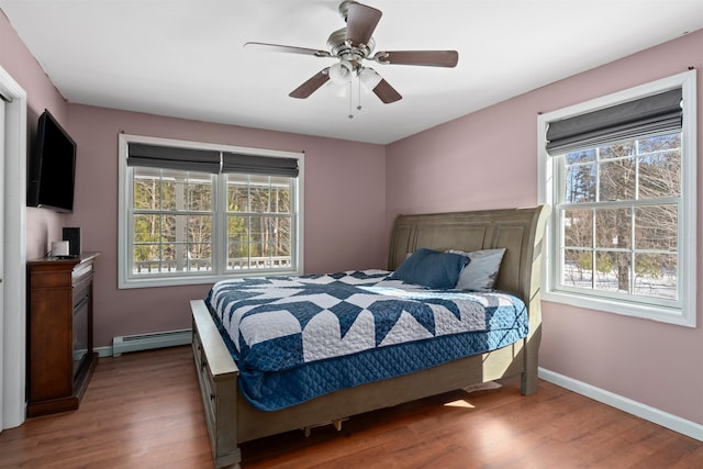 bedroom featuring ceiling fan, a baseboard radiator, wood finished floors, and baseboards