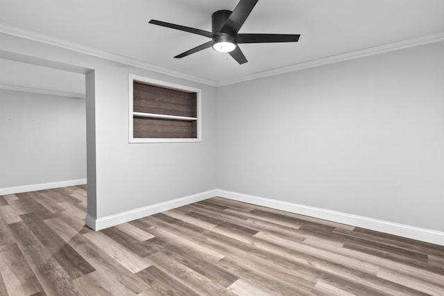 spare room featuring a ceiling fan, baseboards, crown molding, and wood finished floors