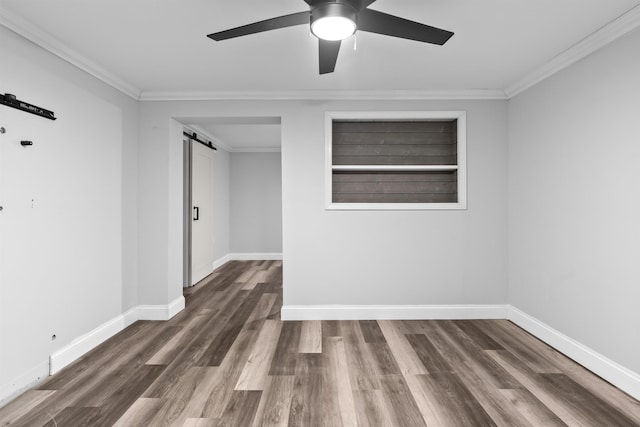 unfurnished room with ornamental molding, baseboards, and a barn door