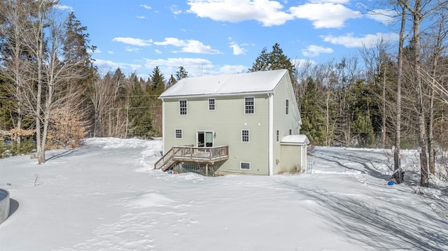 snow covered back of property with a deck