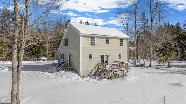 snow covered house featuring stairway and a wooden deck