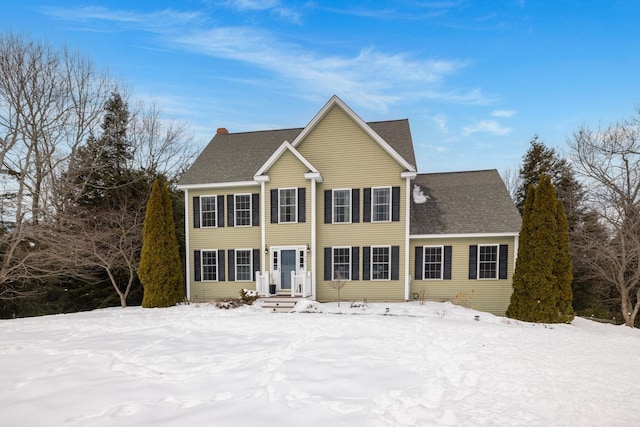 colonial inspired home featuring roof with shingles